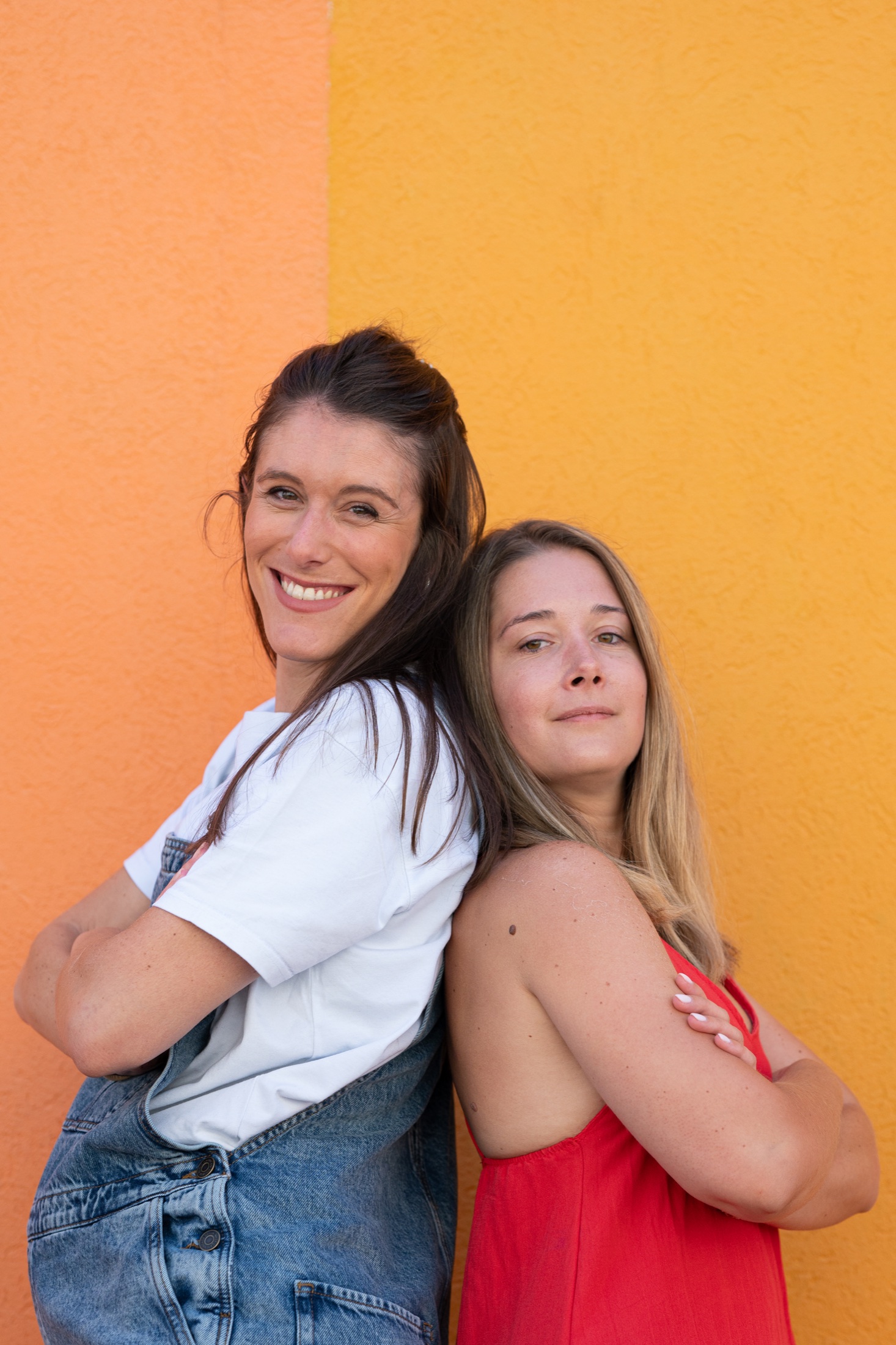 Deux amies posent devant un mur orange
