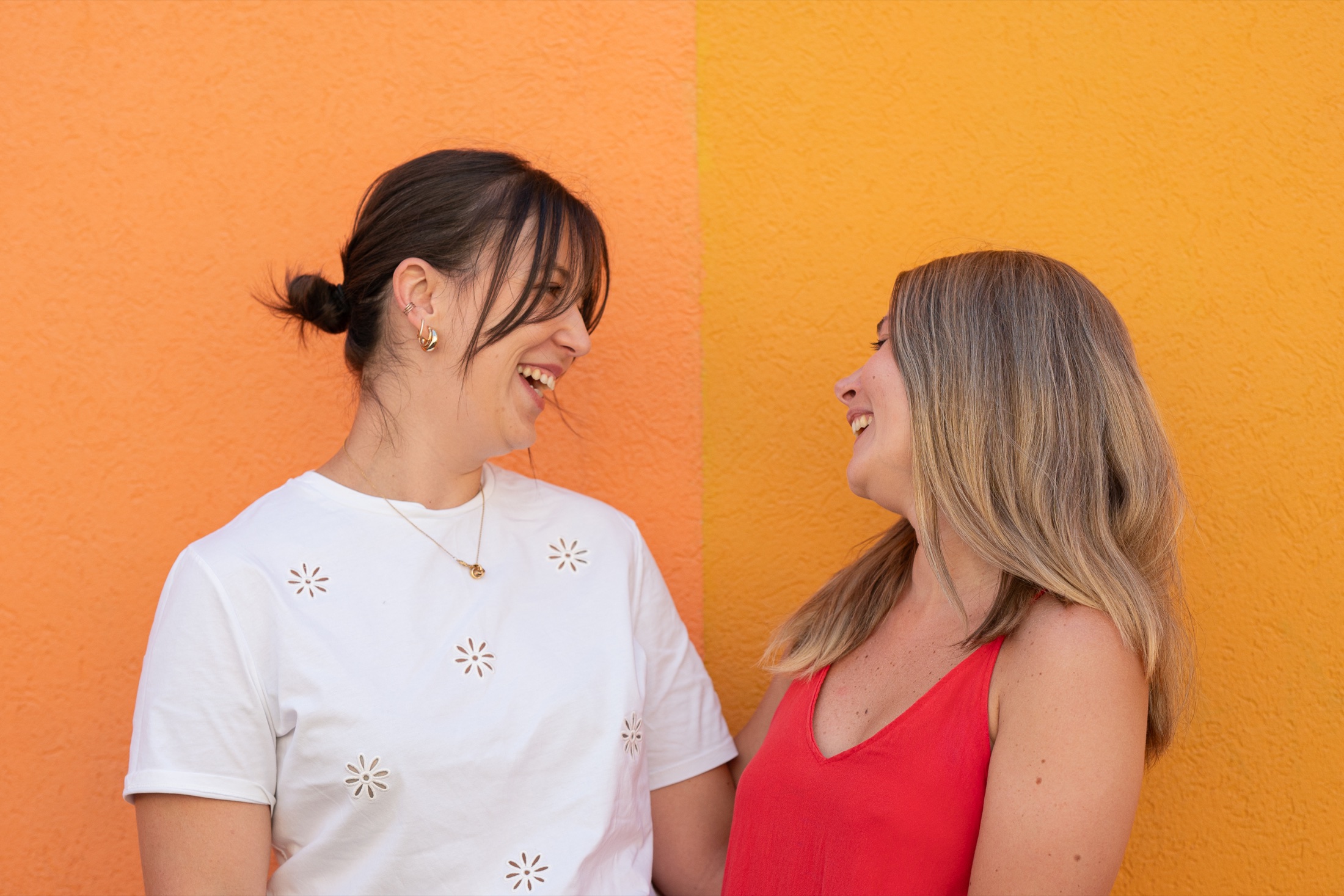 Deux amies rient devant un mur coloré