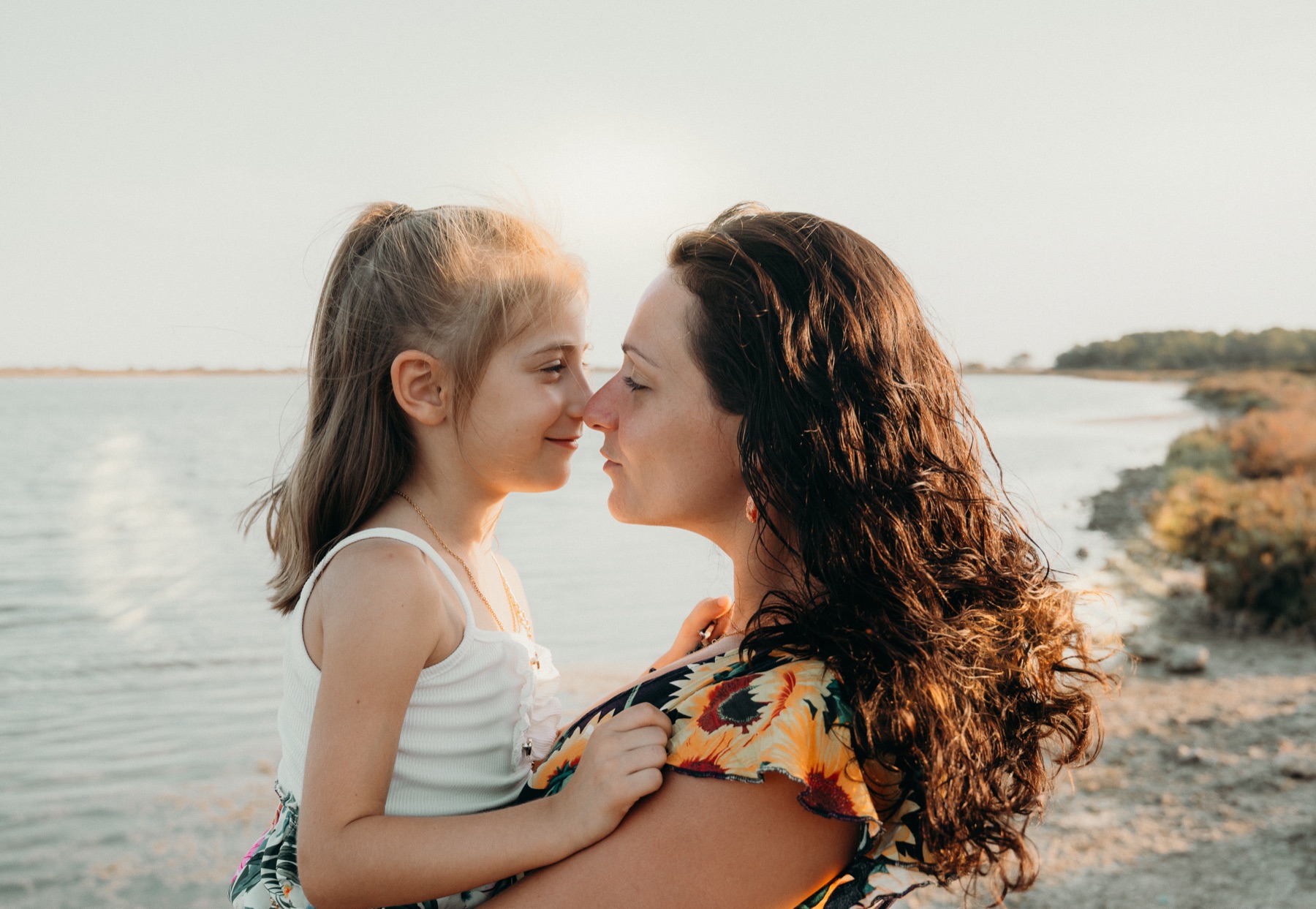 Moment complice entre une mère et sa fille au bord de l’eau