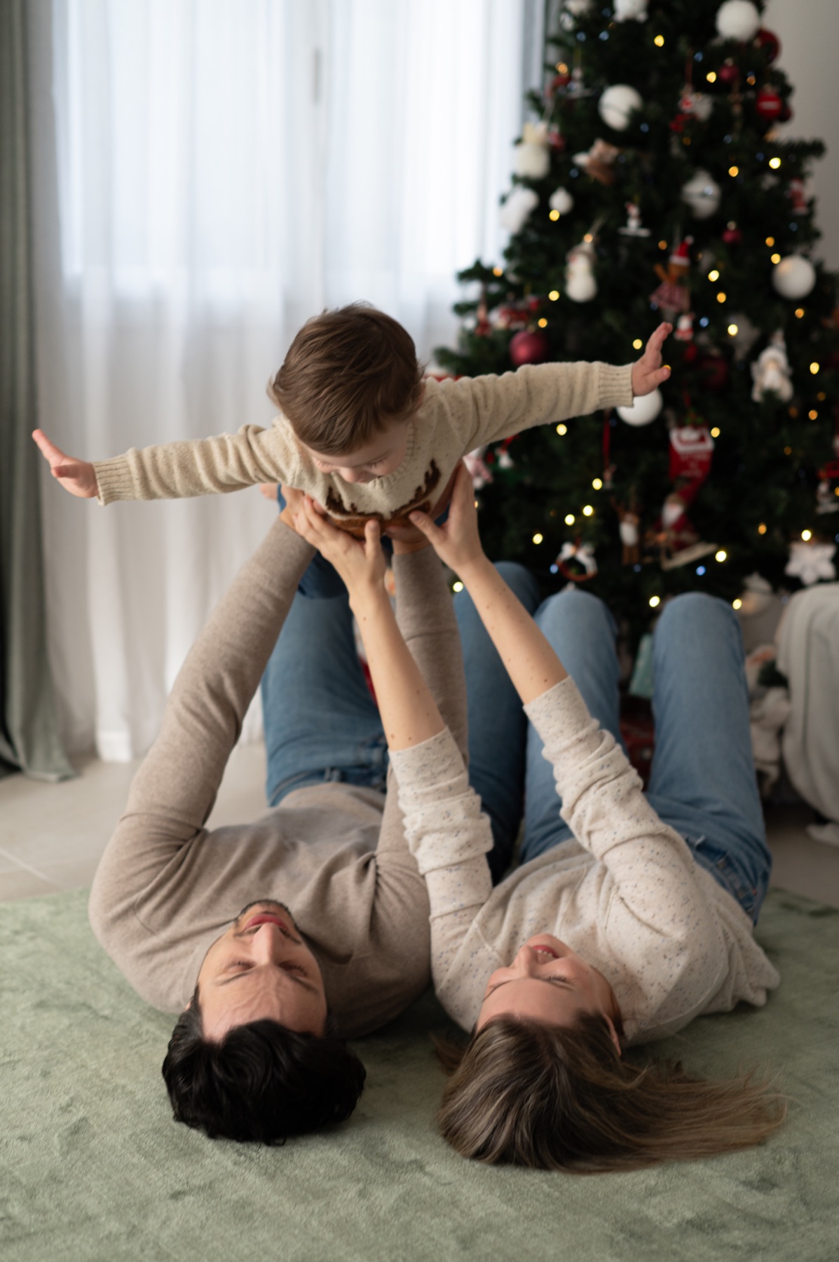 Une famille joue près du sapin de Noël