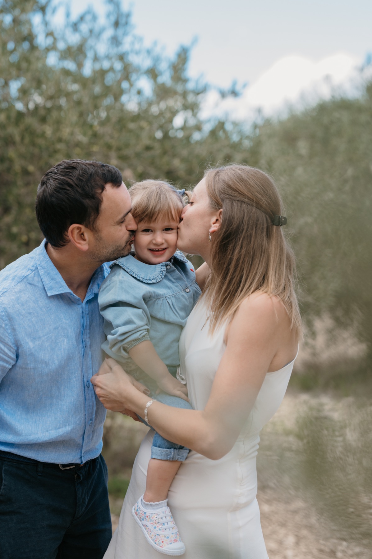 Des parents embrassent leur petite fille
