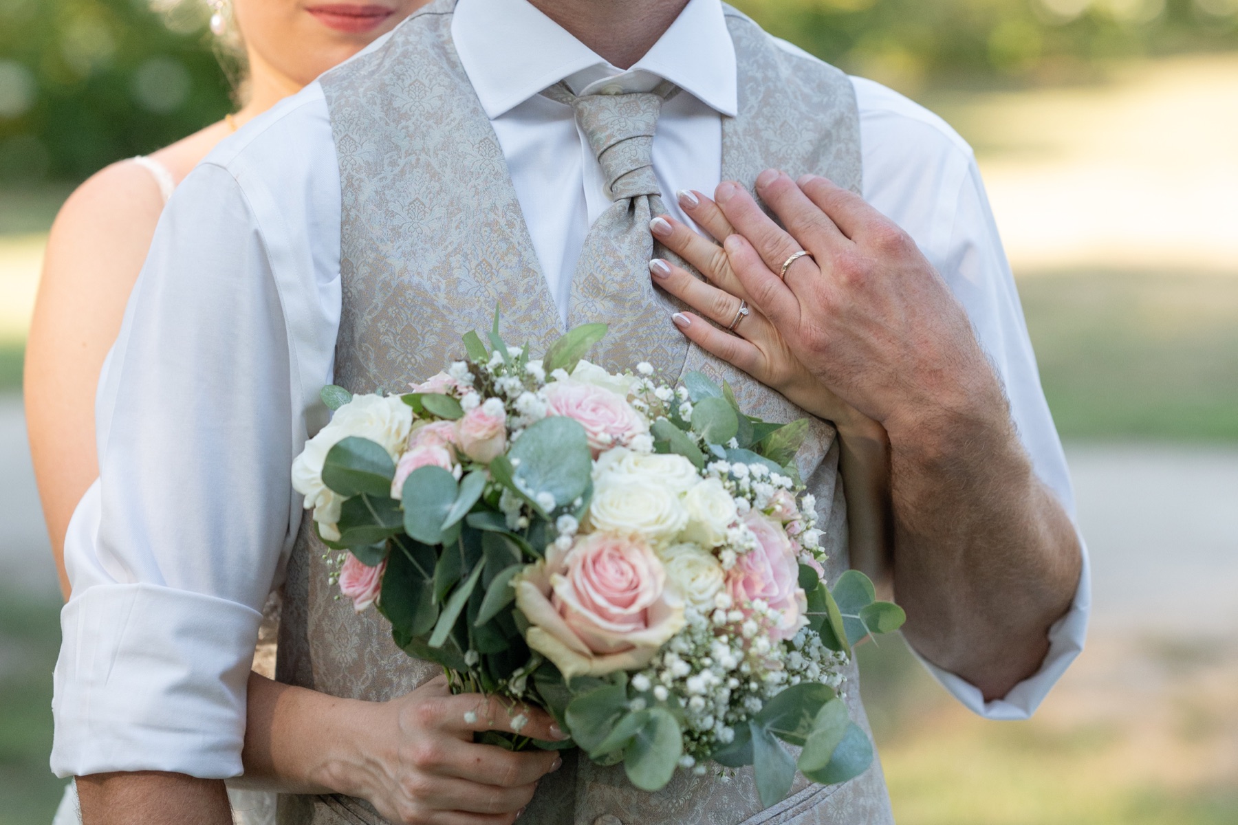 Les mains de Laura et Justin réunies sur leur bouquet
